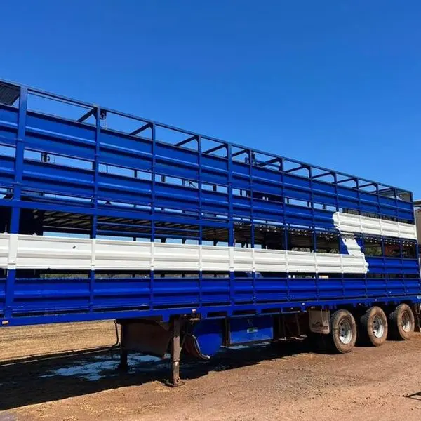 A blue livestock crate on a road train trailer after a wash