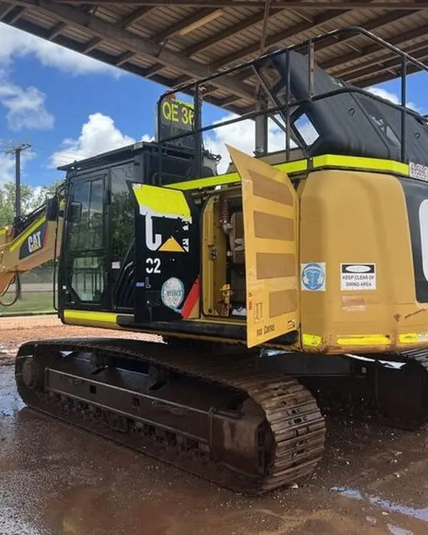 An excavator part way through a weed and seed biosecurity washdown, tracks and undercarriage running clear