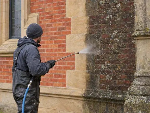 An old brick and sandstone wall part way through a careful low pressure clean, one half back to colour