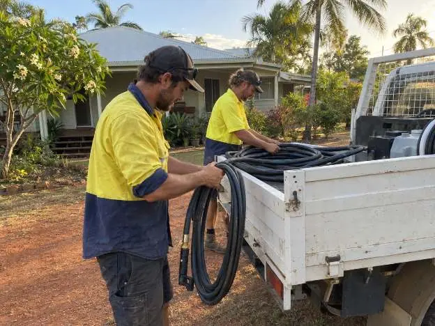 Two operators packing hoses back onto the ute at the end of a scheduled visit to a Territory home