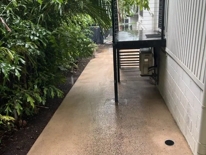 A concrete driveway part way through a surface clean, the cleaned half clearly lighter