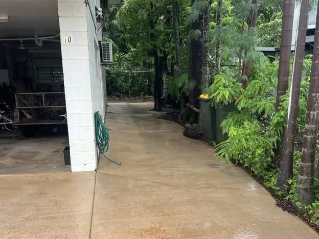 A concrete side path half cleaned, the pale strip running back towards the gate