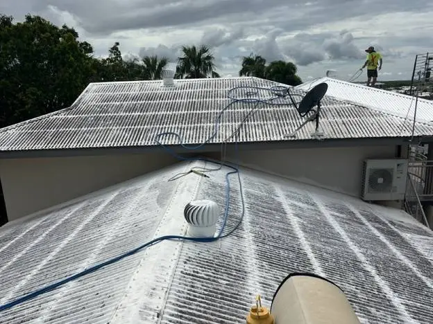 An operator applying a low dose treatment across a Territory roof with the wet season clouds building behind