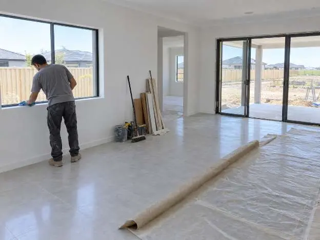 A new house being cleaned down before handover, protective sheeting rolled back off the new floor