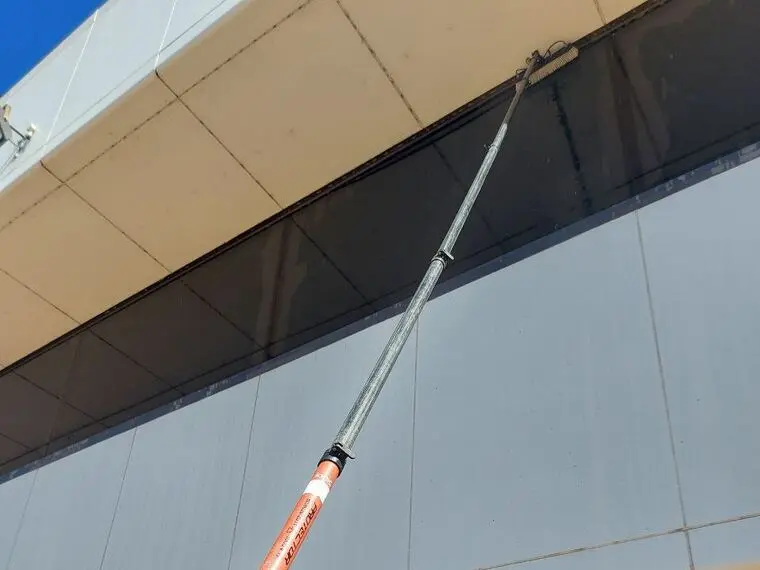 An operator cleaning high external windows from the ground with a telescopic water fed pole