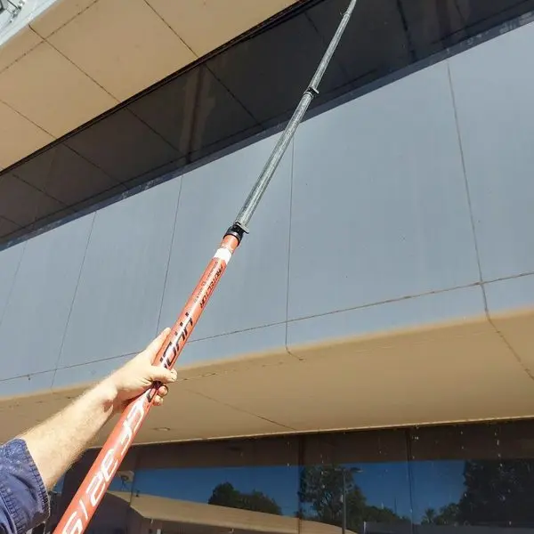 An operator reaching high cladding with a water fed pole