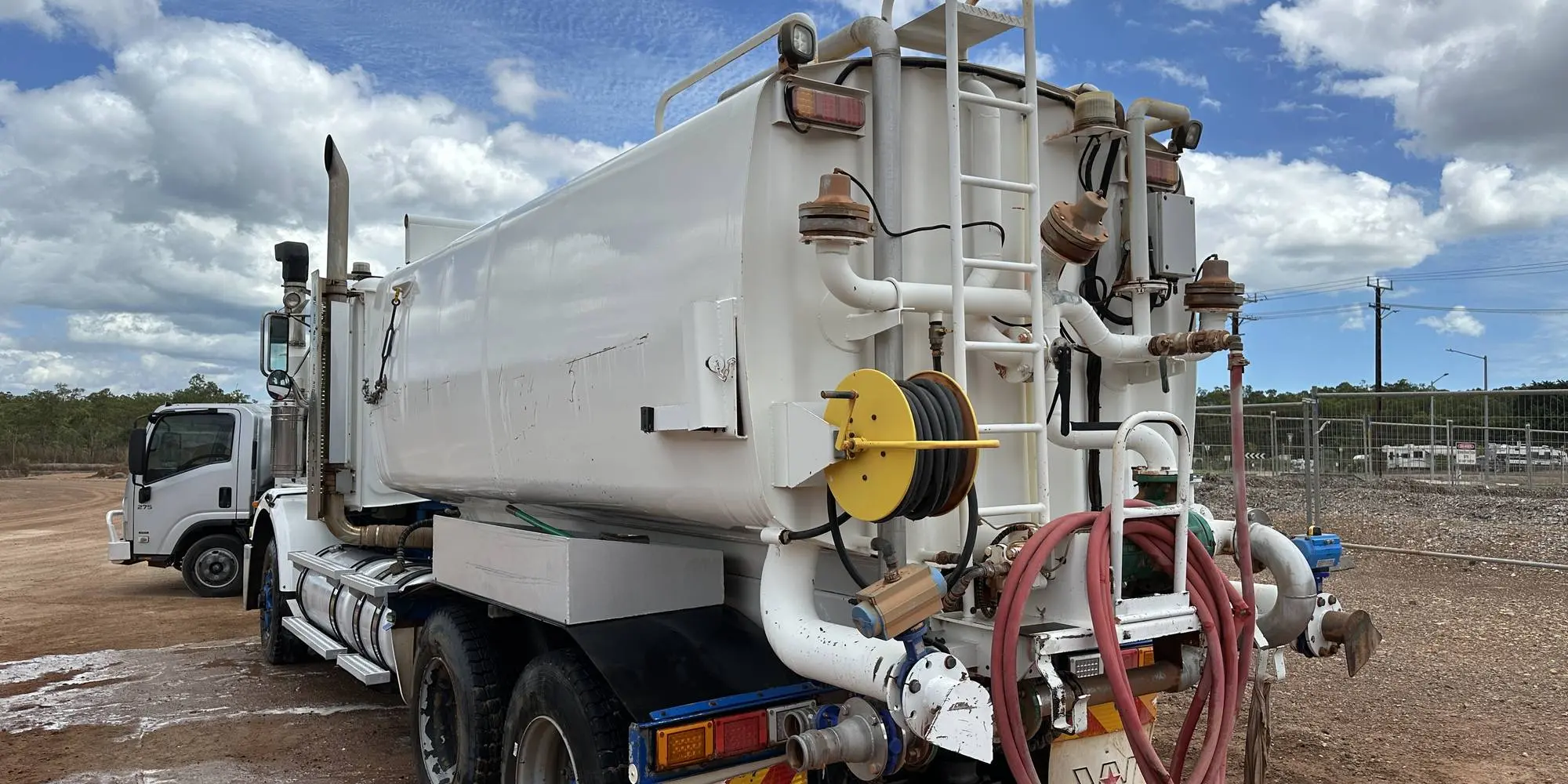 A Power Clean NT water truck with hose reels and pumps, parked on a wet washdown pad