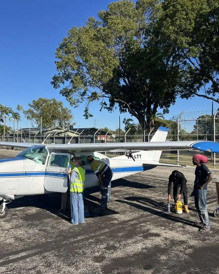 Two operators in hi vis washing down a light aircraft on a remote Territory airstrip