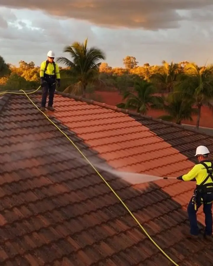 Two Power Clean NT operators soft washing a red tile roof on a Darwin home late in the afternoon