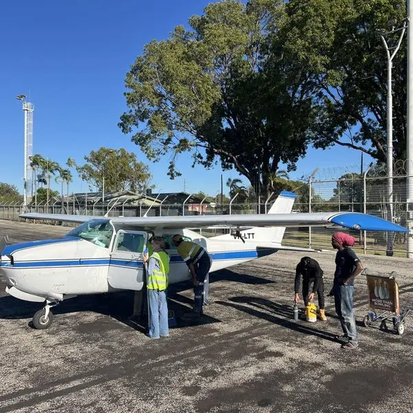 Two Power Clean operators in hi vis washing down a light aircraft on a remote airstrip
